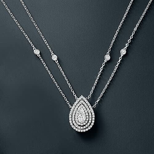 Elegant diamond necklace with double chain and teardrop pendant.