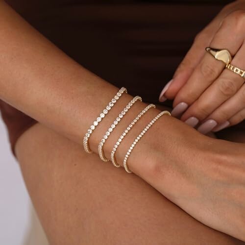 Close-up of a woman's arm with gold bracelets and a ring.