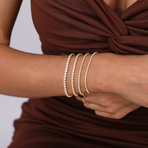 Woman wearing multiple gold bracelets on arm.