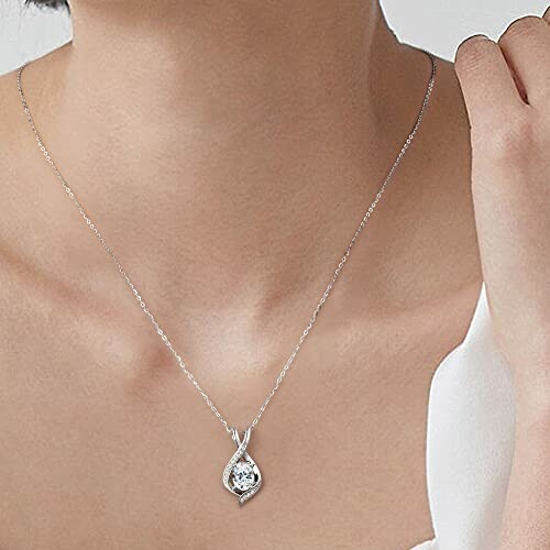 Woman wearing an elegant silver necklace with a teardrop pendant.