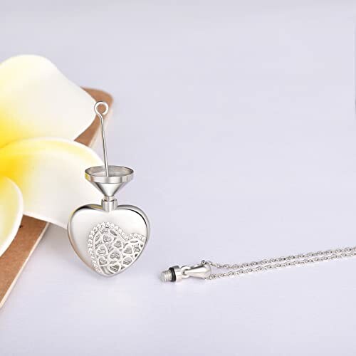 Heart-shaped pendant necklace with floral design and chain on a white background.