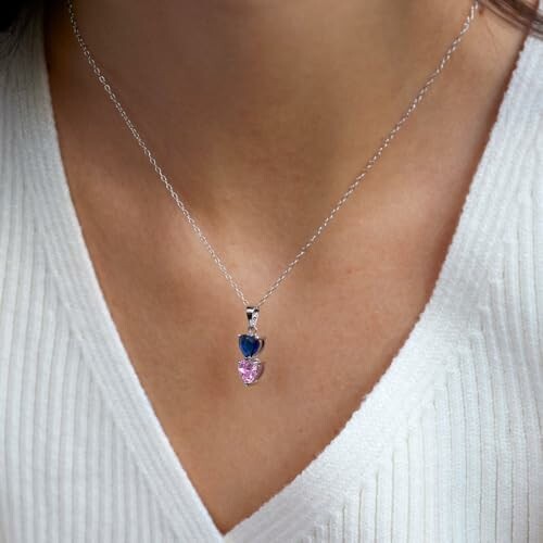 Close-up of a heart-shaped silver necklace with blue and pink stones.