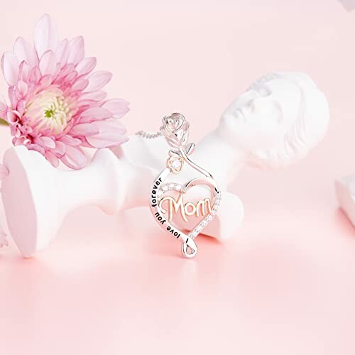 Heart-shaped pendant with 'Mom' and rose on statue with pink flower