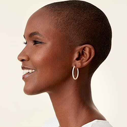 Profile view of a smiling woman with short hair and hoop earring.