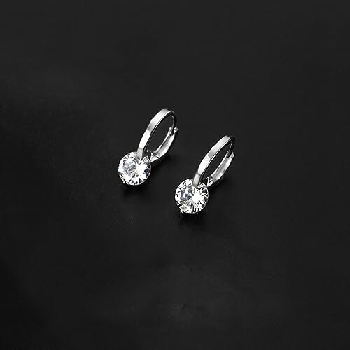 Pair of silver earrings with diamonds on black background