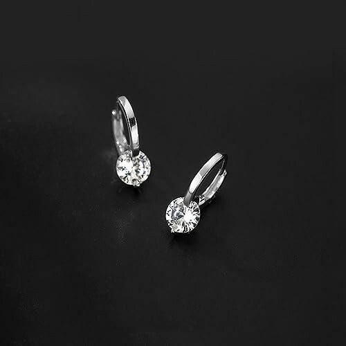 Pair of silver earrings with diamonds on a black background.