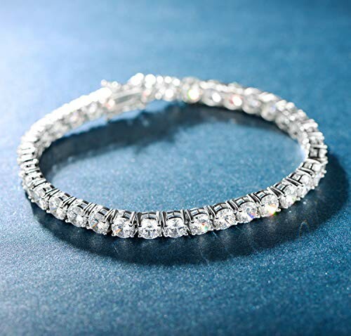 Silver diamond tennis bracelet on a blue surface.