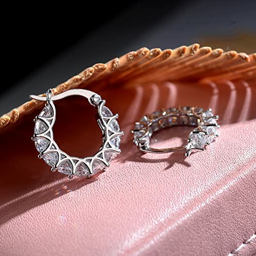 Silver hoop earrings with crystal accents on a textured surface.