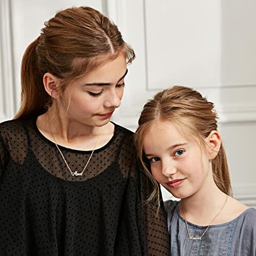 Two girls wearing necklaces, looking at each other.