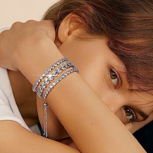 Woman with silver bracelets resting her head on her arm.