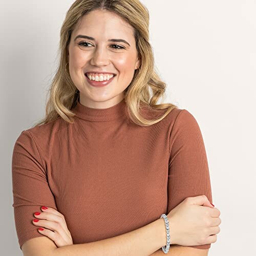 Woman smiling wearing a brown top and bracelet