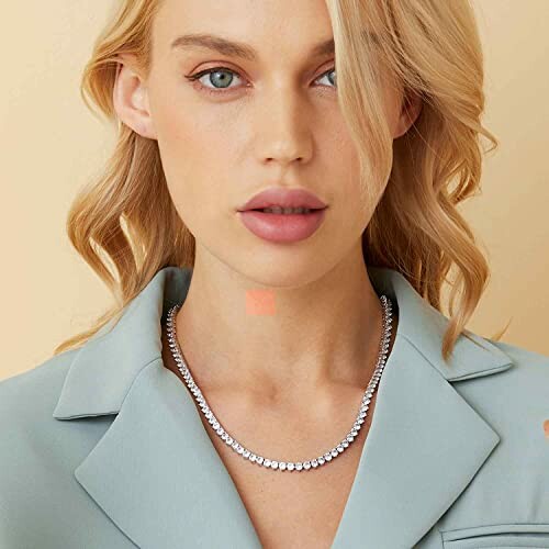 Woman wearing a diamond necklace and light blue blazer.