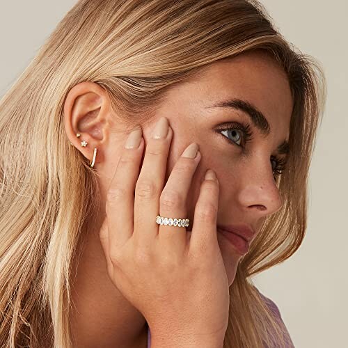 Woman wearing earrings and a ring, close-up profile.